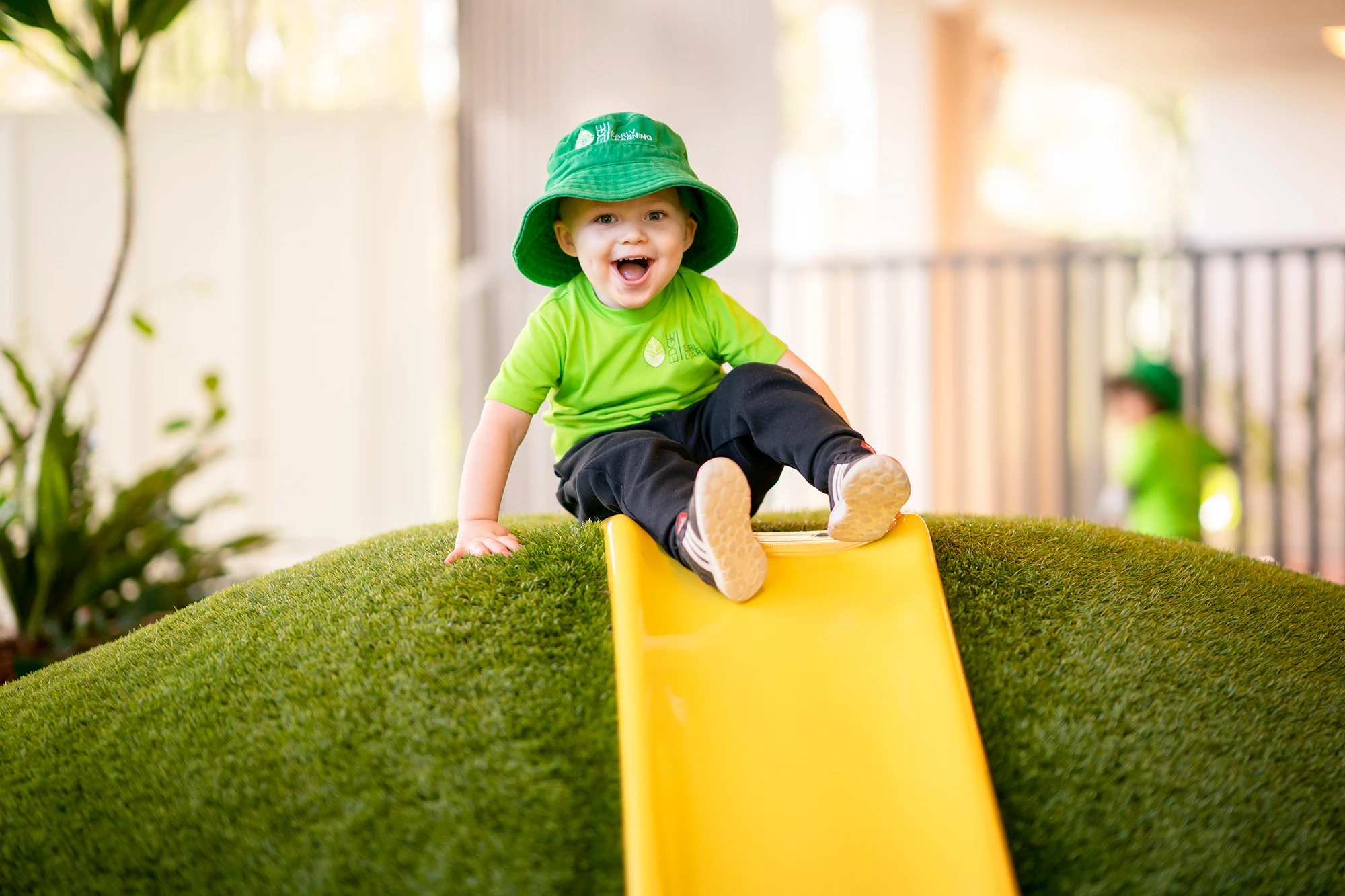 Child on a yellow slide at Edge Early Learning centre in Kelvin Grove.