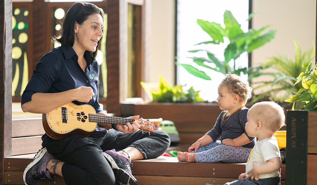 Teacher playing instrument to two children