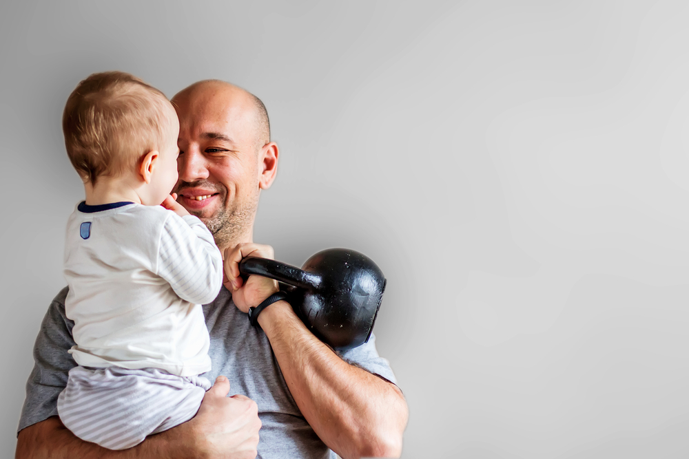 father holding toddler and dumbell