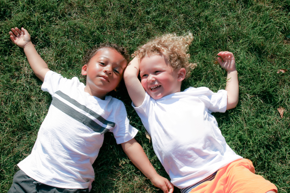 Two little boys laying on the grass