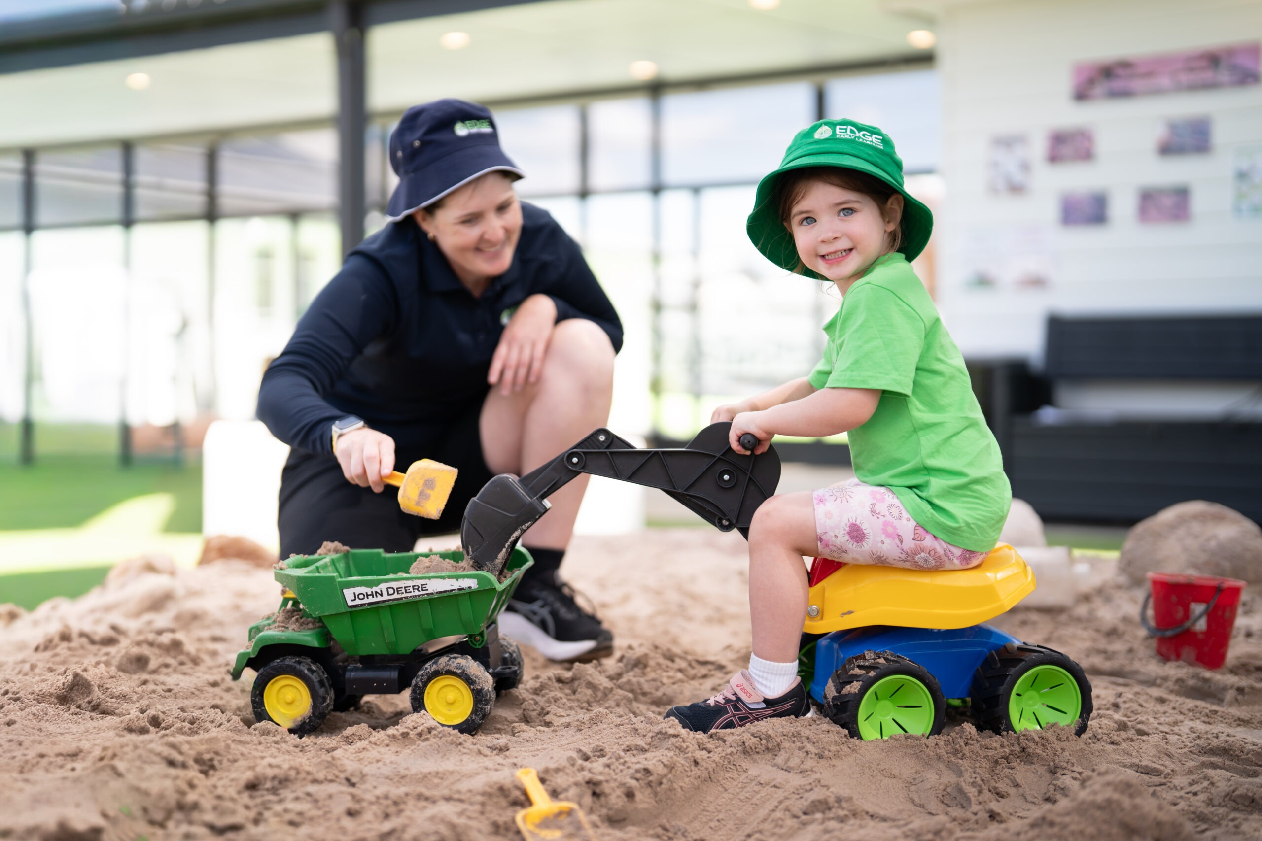 Kindergarten child using sandpit digger toy at Edge Grange childcare centre.