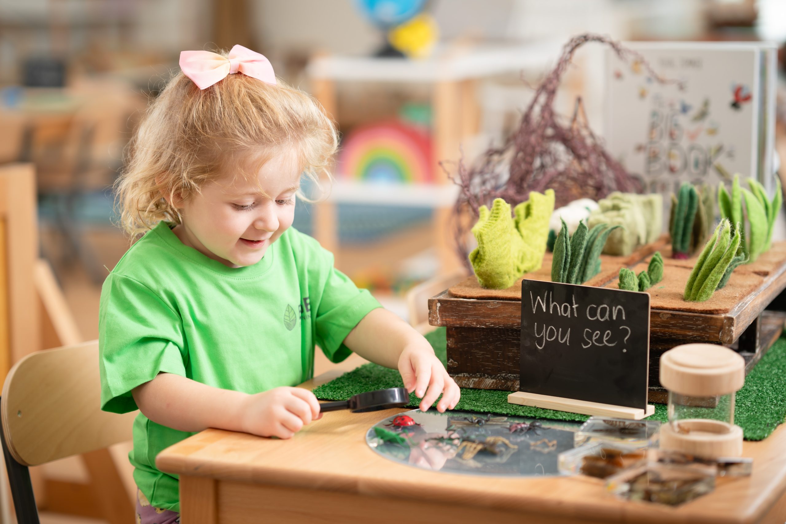 A child uses a magnifying glass to explore plastic insects at a childcare centre in Kanimbla