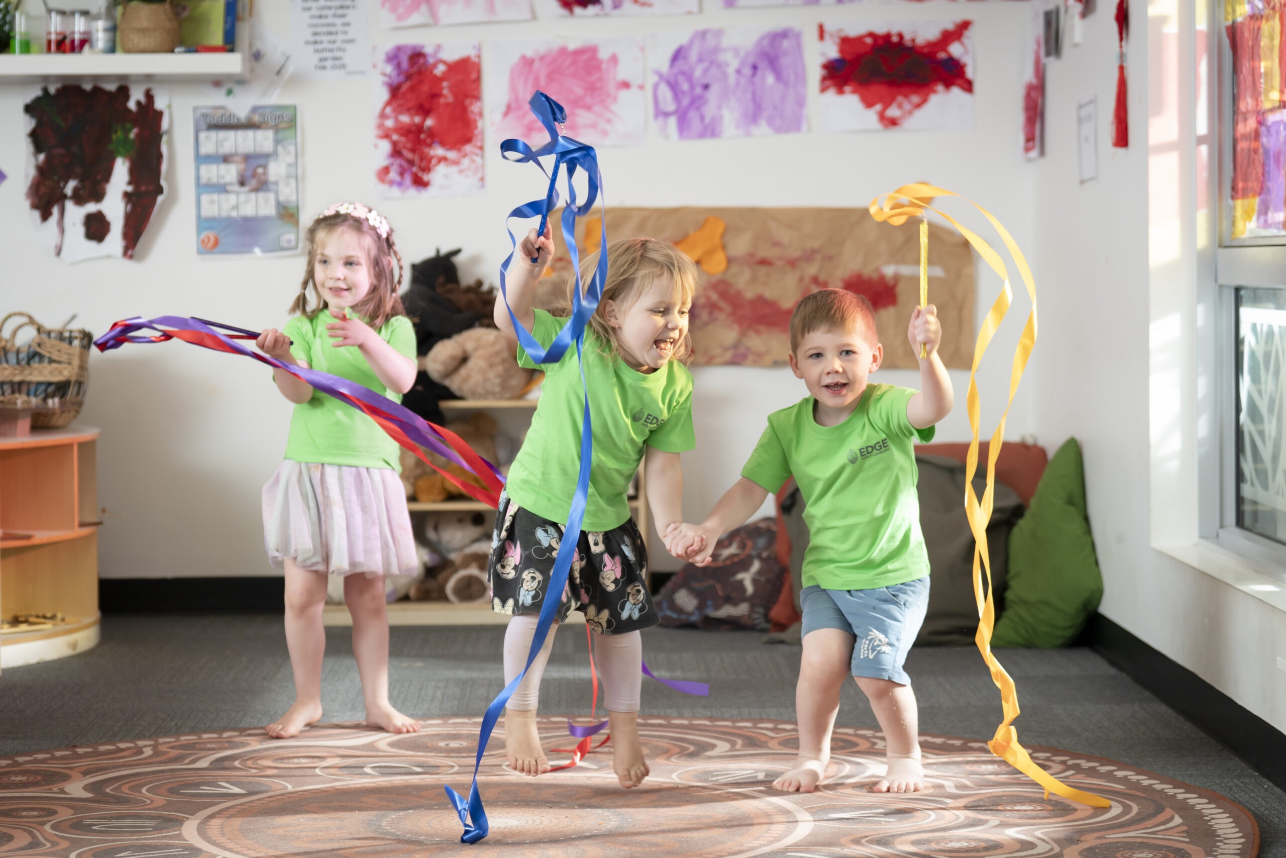 Boy and gilr holding hands while dancing with ribbons at Edge Strathalbyn childcare