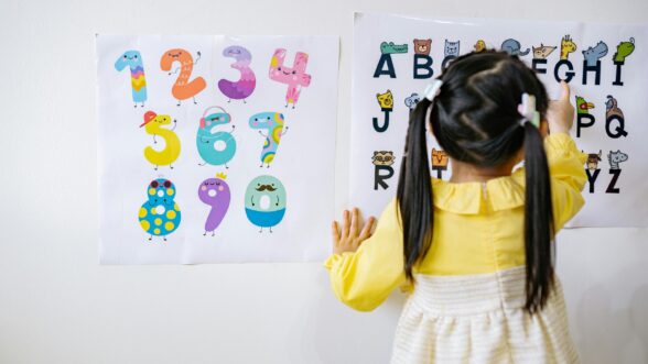 A child writing letters on a piece of paper.