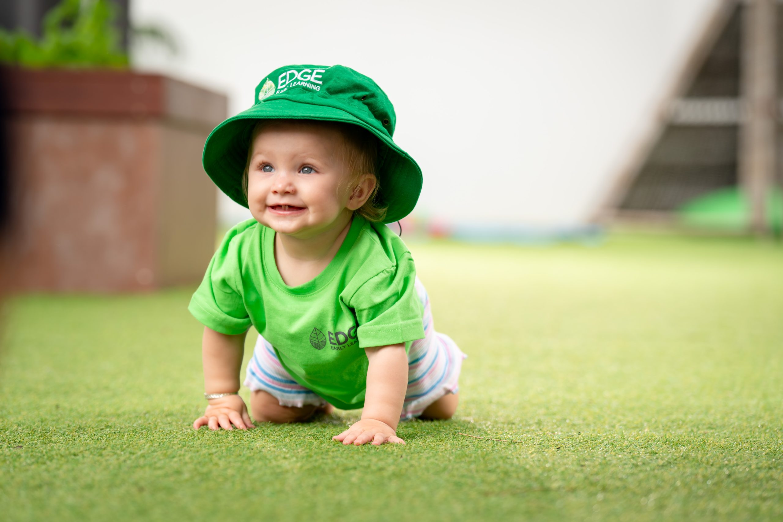 Baby crawling and smiling at the nursery outdoor play area at an Eagleby childcare