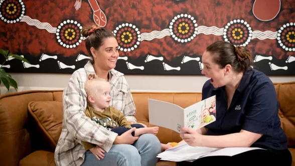 Parent with a child on their lap talking with a Centre Director at an Edge Early Learning centre.